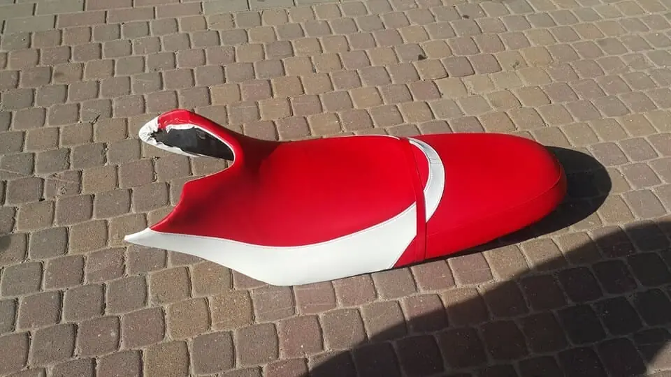 מושב אופנוע מרופד בצבע אדום ולבן על רקע מרצפות אבן